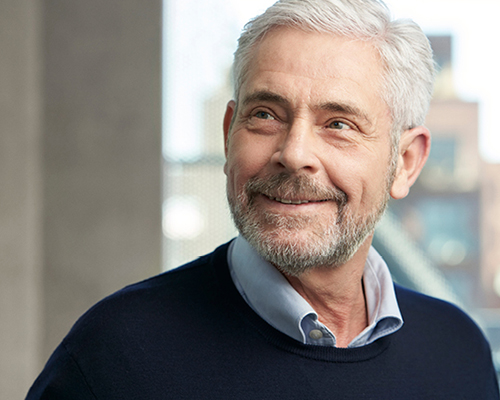 Smiling man in a professional setting, representing satisfied audiology patient after successful hearing care treatment.