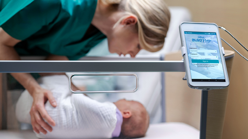 Healthcare professional preparing newborn for screening beside ALGO Pro Infant Hearing Screening Device interface.