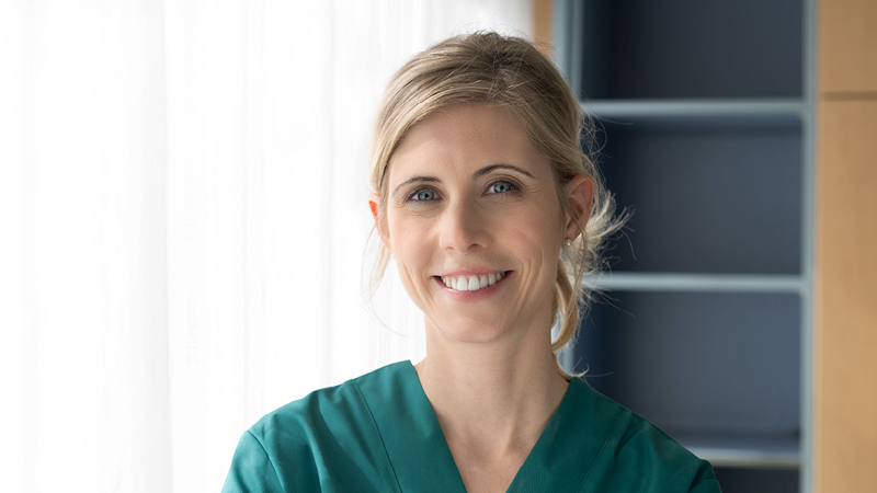 Smiling healthcare professional representing the clinical users of ALGO Pro Infant Hearing Screening Device in a professional setting.