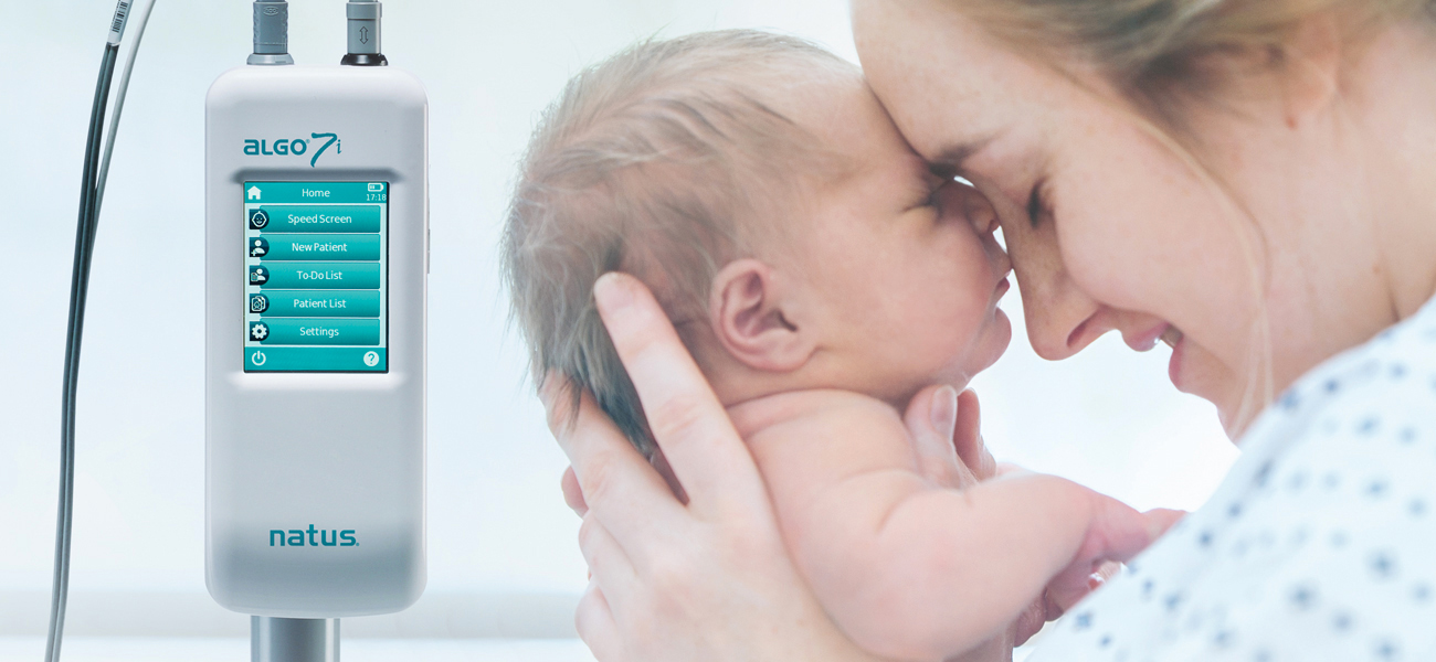 Mother holding newborn next to the ALGO 7i Newborn Hearing Screener used for early infant hearing assessment.