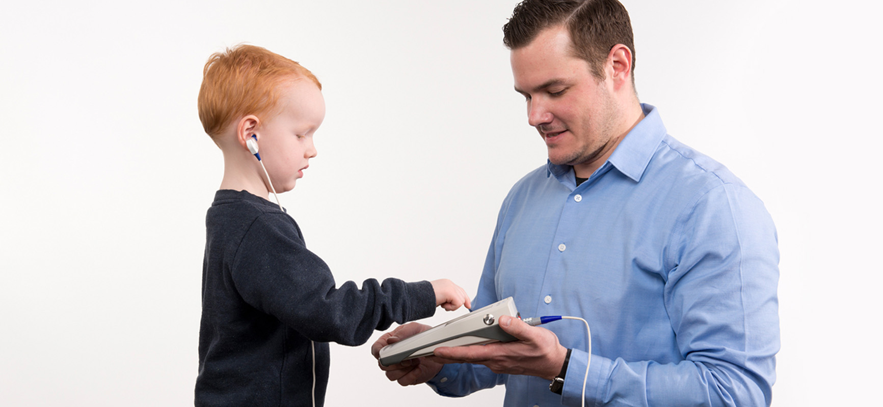 Clinician performing hearing assessment using Bio-logic AuDX PRO portable audiometry tool.