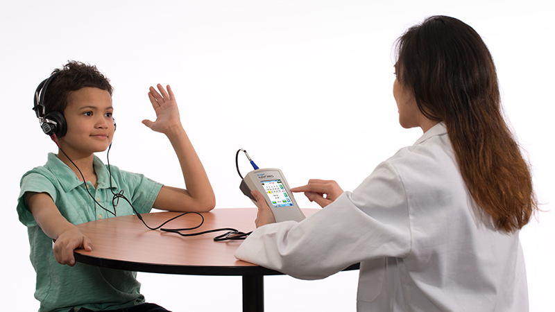 Clinician performing hearing assessment using Bio-logic® AuDX® PRO portable audiometry tool.