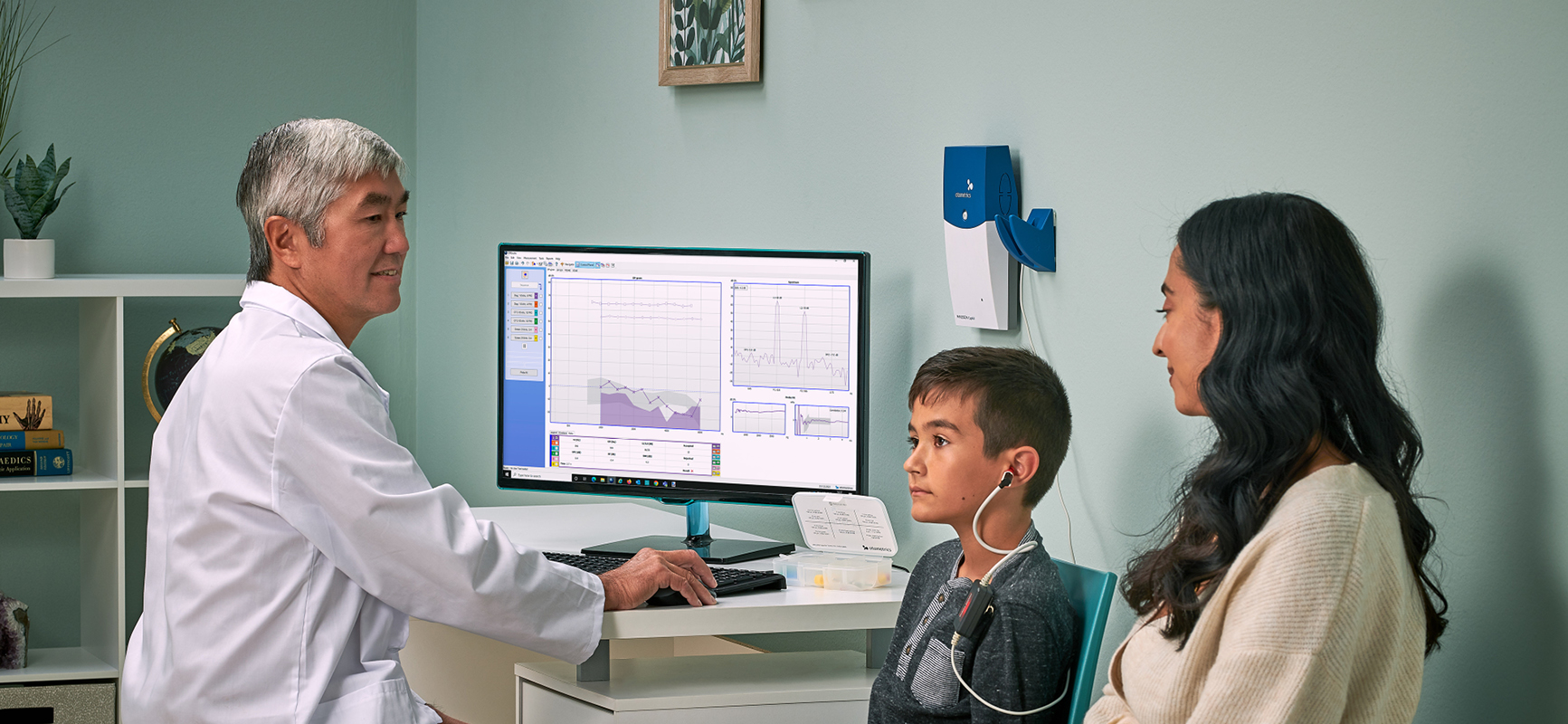 Audiologist performing OAE test on a child using Madsen Capella2 system while parent observes.