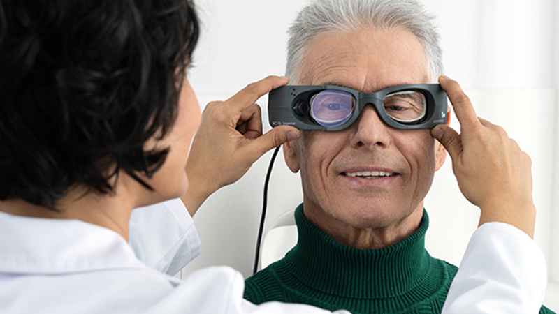 Clinician fitting ICS Impulse goggles on a patient to prepare for head impulse testing and vestibular evaluation.
