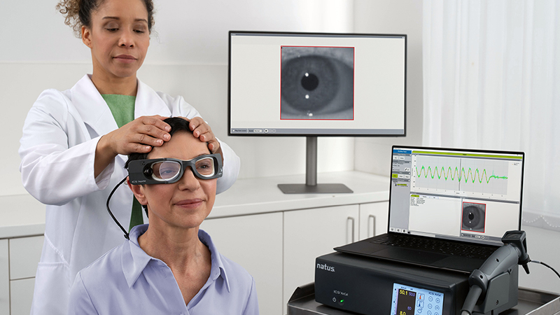 Clinician conducting head impulse test with ICS Impulse goggles while eye movement data is tracked on screen during vestibular assessment.