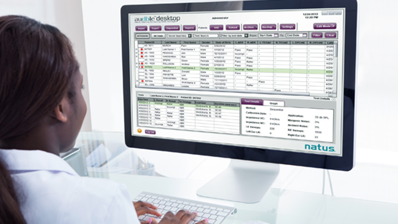 Clinician using Natus audble Desktop software for hearing screening data management on a desktop computer.