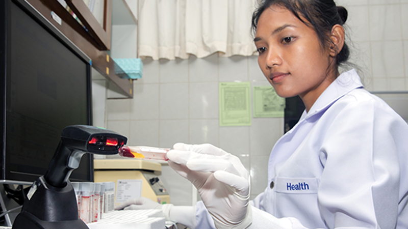 Lab technician scanning a blood sample for metabolic screening data entry in newborn testing workflow.