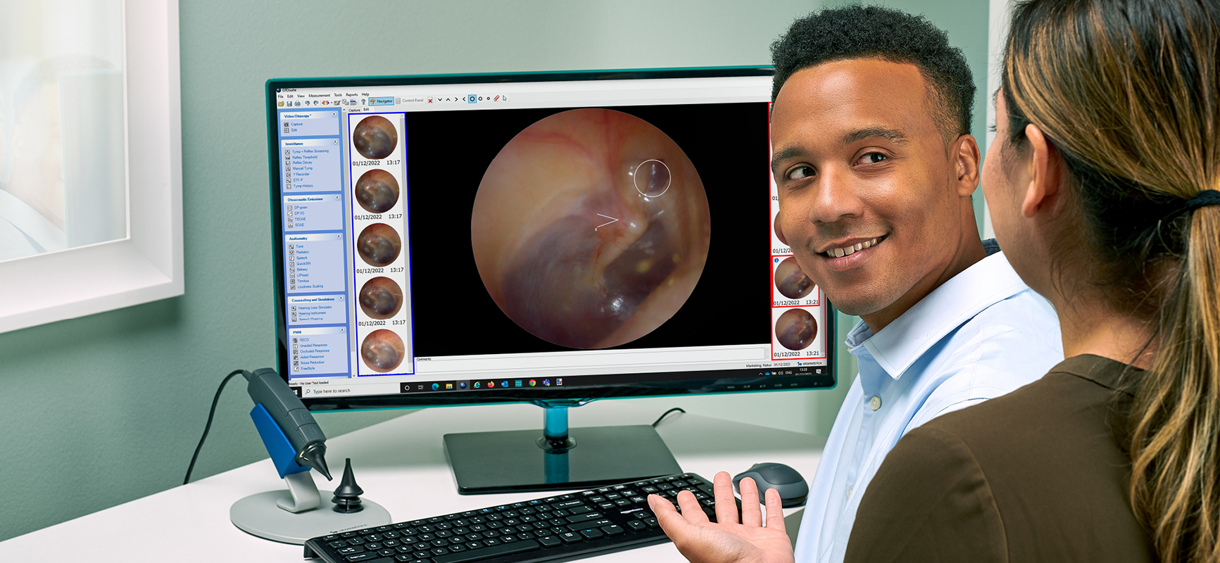 Clinician using Aurical Otocam 300 video otoscope to display high-resolution ear image on screen.