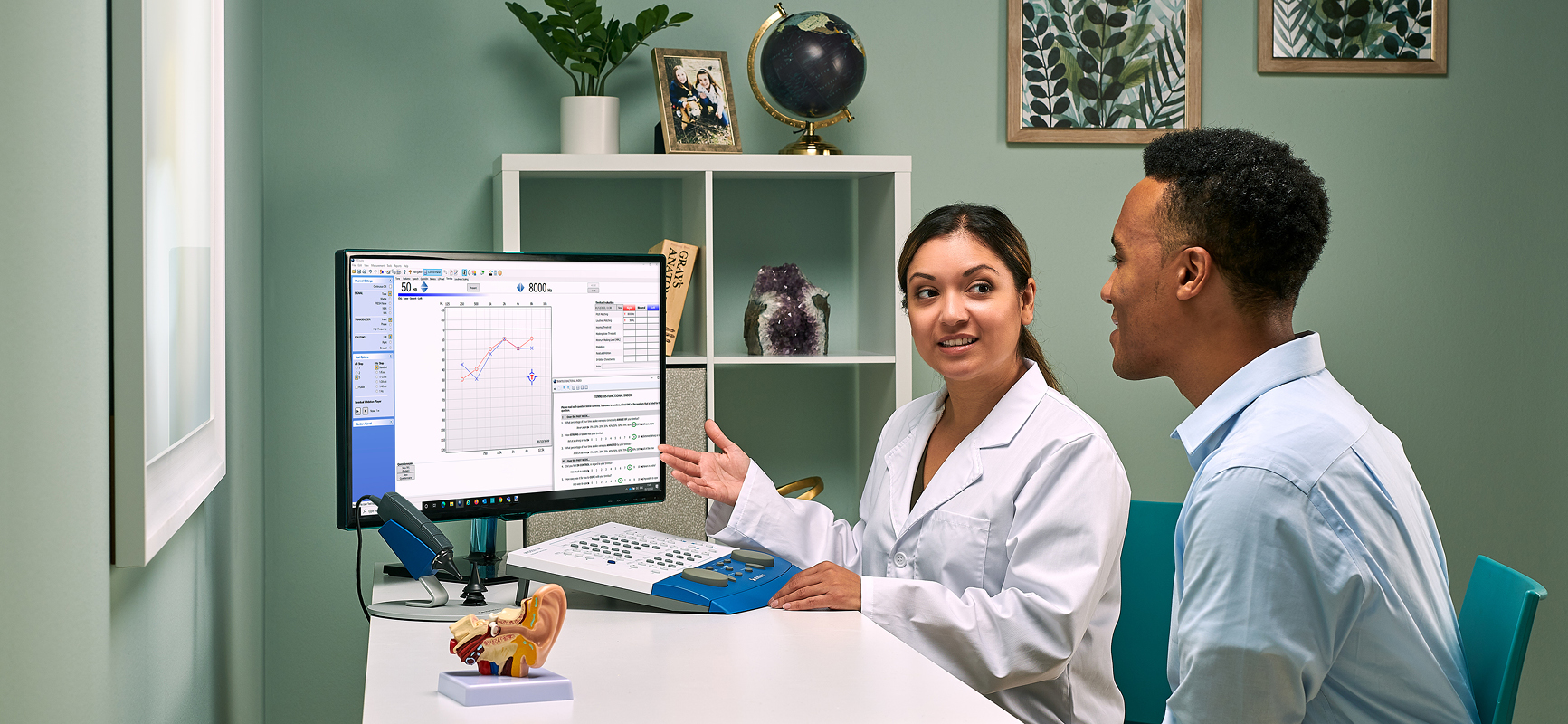 Audiologist discussing hearing test results with a patient using PC based audiometric testing software and diagnostic audiometry equipment.
