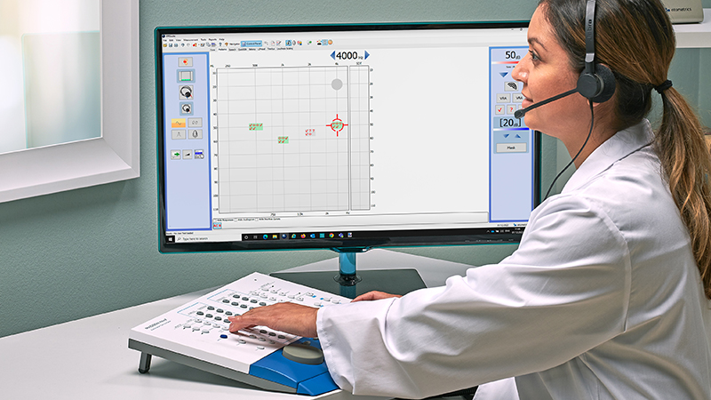 Clinical audiometer features and functions demonstrated by an audiologist during a hearing test.