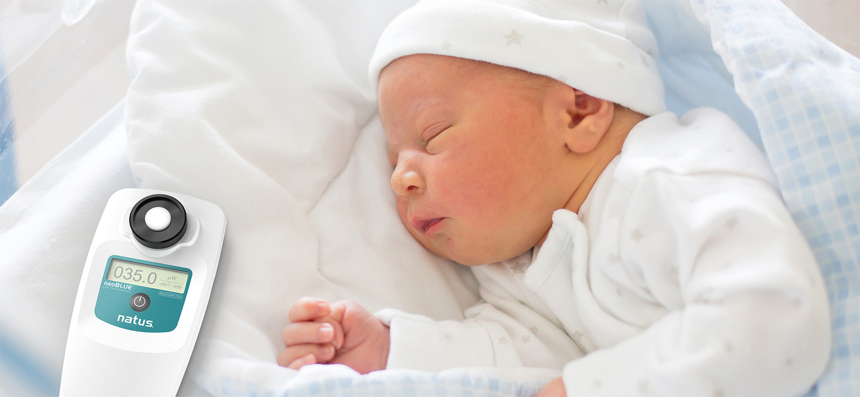 neoBLUE Radiometer beside sleeping newborn for accurate irradiance monitoring during bilirubin phototherapy treatment.